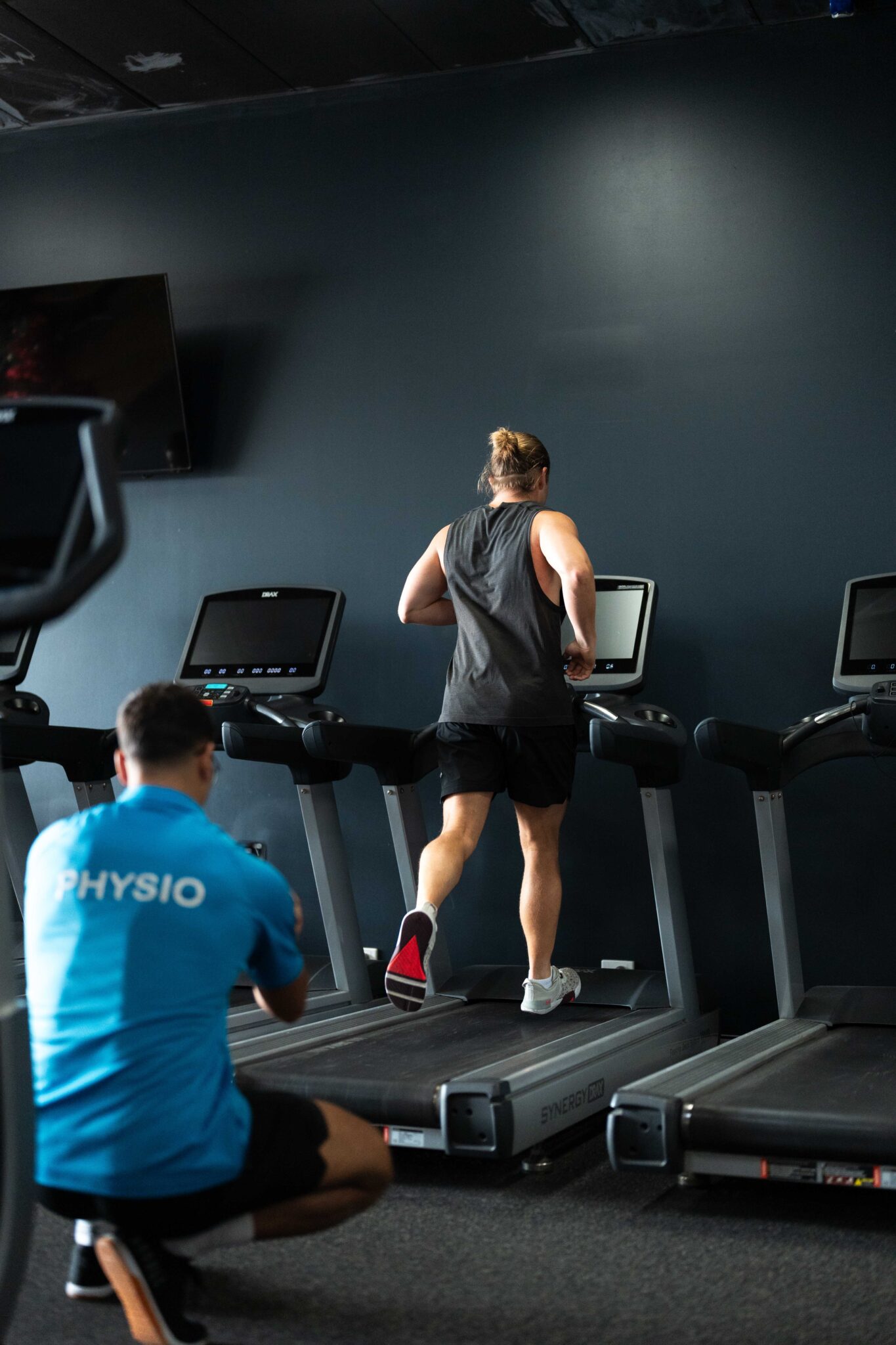 Physio filming a man running on a treadmill